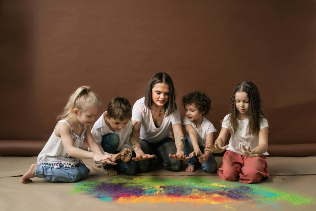 pexels-photo-7176471-7176471 Group of children and a woman enjoying colorful powders together indoors, expressing fun and creativity.